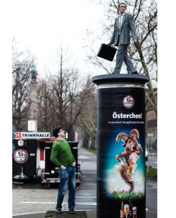 Christoph Pöggeler vor dem Säulenheigen „Der Geschäftsmann“. „Ikone der Zeit“. Rheinufer. Foto: Markus Luigs